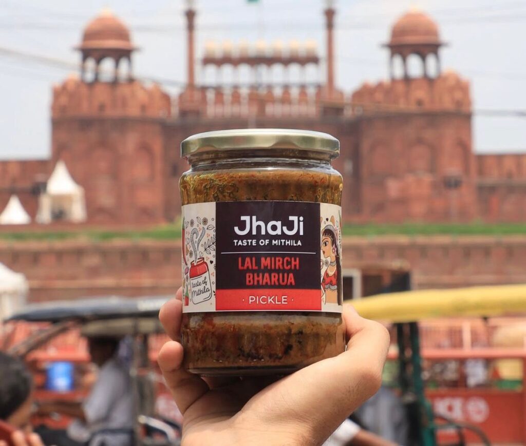Product photography for ads showcasing JhaJi Lal Mirch Bharua pickle jar in front of Red Fort, Delhi.
